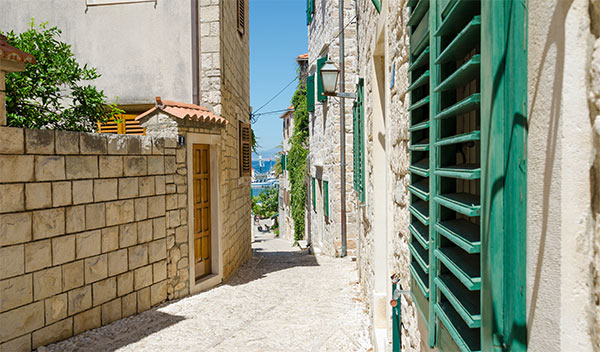 Gata mellan gräddvita stenhus i Postira, Kroatien